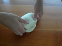 生地をガス抜きをしながら二つに折り、綴じ目を上にして自分に垂直に置きます。この綴じ目を隠すようにもう一度手前から二つ折りにします。これを数回繰り返し、表面をきれいに整えていきます。<br />
<br />