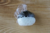 深いV字の方の海苔をおにぎりの形に合わせて包み、再度ラップをして海苔をおにぎりに馴染ませます。<br />